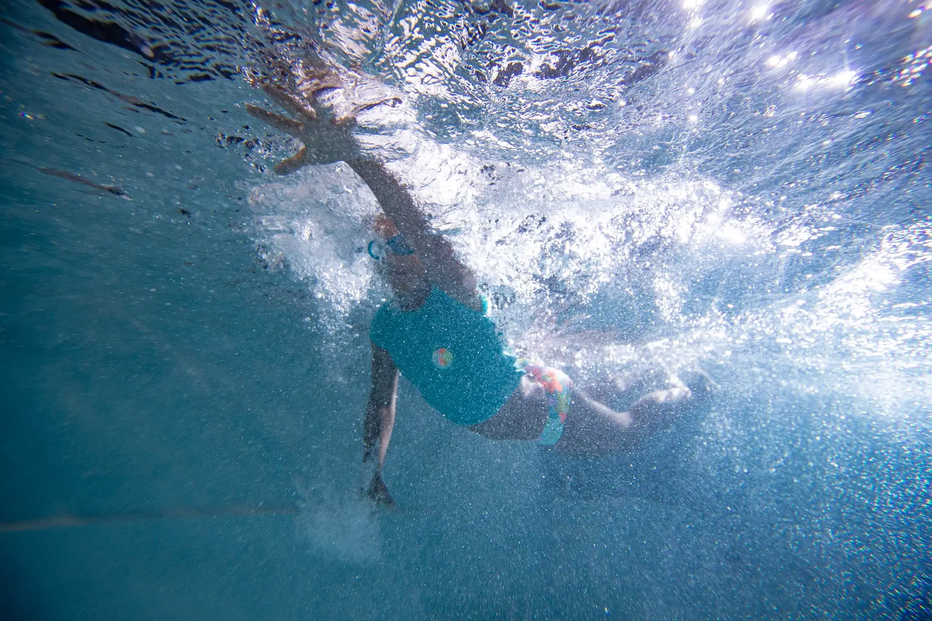Girl swimming underwater in a swim spa, showcasing the benefits of relaxation and recreation in a Jacuzzi&reg; swim spa setting.